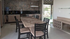 Una cocina moderna con comedor, que presenta un salpicadero con diseño, un horno empotrado y una mesa grande con sillas.