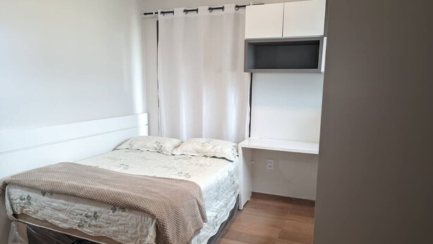 Un dormitorio con cama, ventana con cortinas y estante empotrado.