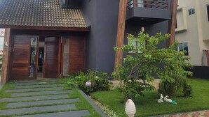 Una casa moderna de dos pisos con fachada oscura, un balcón de madera y techo de tejas.