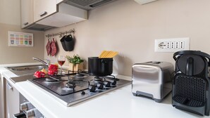 Una cocina con estufa a gas, tostadora y una olla de espagueti.