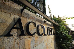 A stone wall with the word 'ACCUEL' in large, bold letters, indicating a hotel or similar establishment.