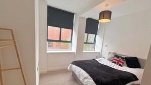 Une chambre à coucher avec un lit, deux fenêtres, une échelle et un luminaire suspendu.