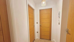 Un couloir avec des portes en bois et un téléphone fixé au mur.
