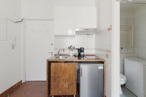 Une cuisine compacte équipée d’un réfrigérateur, d’un évier et d’une machine à café.