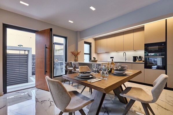Un comedor moderno con una mesa de madera preparada para cuatro personas, rodeada de sillas tapizadas.