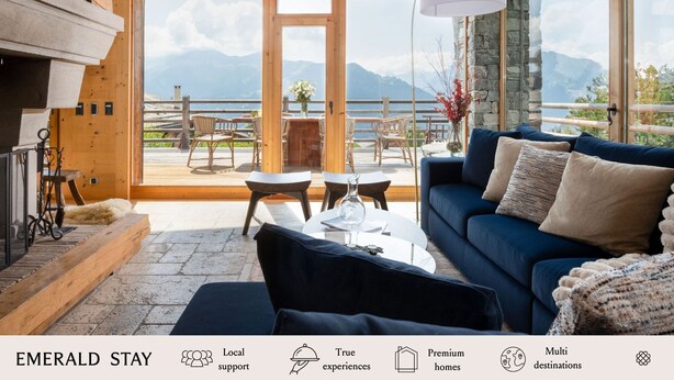 Una habitación acogedora con un sofá azul, una chimenea y vistas a montañas y un lago.