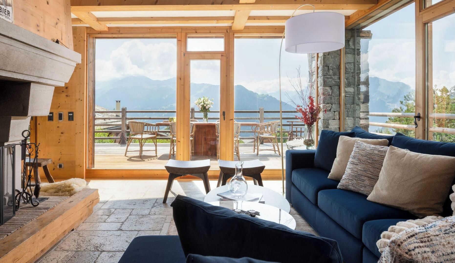 Una habitación acogedora con un sofá azul, una chimenea y vistas a montañas y un lago.