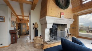 Una habitación acogedora con chimenea, vigas de madera, una cesta de mimbre y un sofá azul.