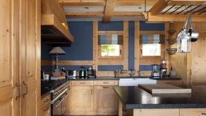Una cocina con armarios de madera, encimera negra y ventana con vistas a la vegetación.