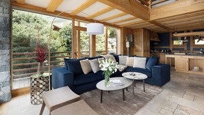 Una sala de estar moderna con un sofá azul, una mesa de centro y vistas al exterior.