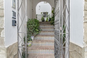 A staircase with patterned tiles, potted plants, and a metal gate.