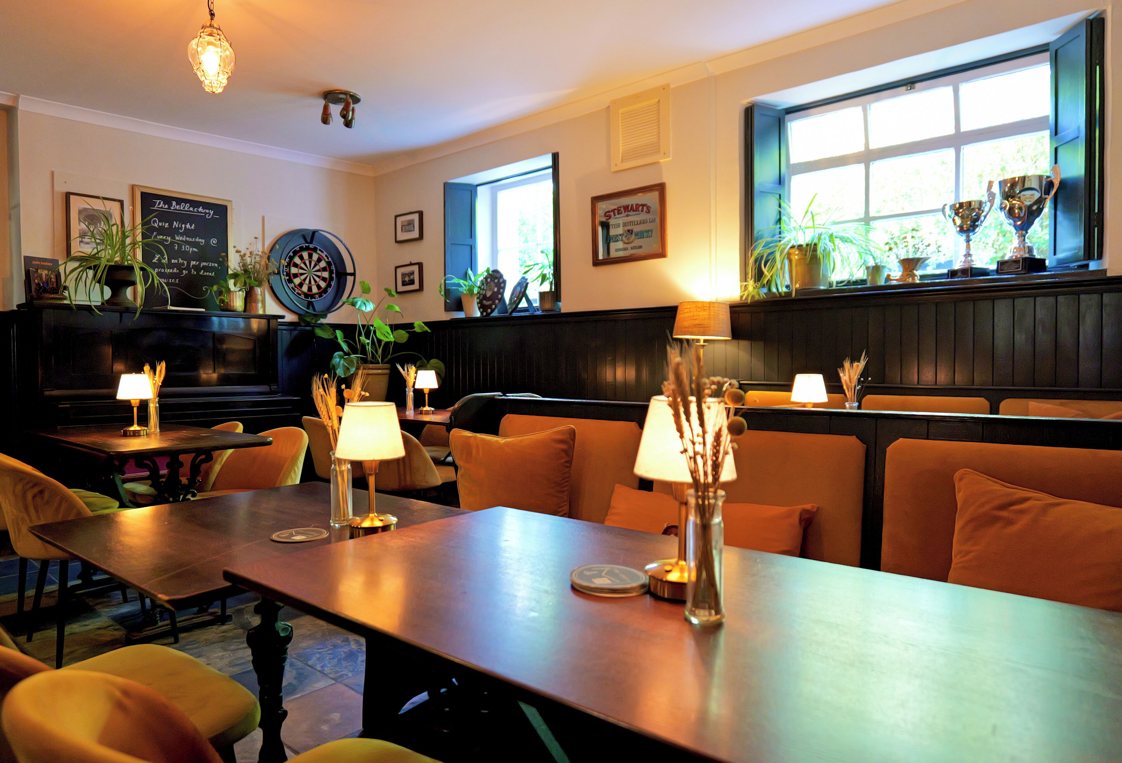 A restaurant with tables, chairs, and a dartboard.