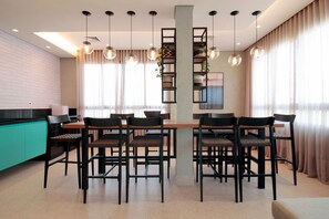 A modern dining area with a central table, chairs, and pendant lighting. - Boulevard Agami (São Paulo)