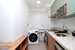 A compact kitchen with a washing machine, sink, and wooden counter. - Boulevard Agami (São Paulo)