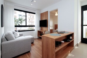 A modern living room with a grey sofa, wooden coffee table, and a TV mounted on the wall.