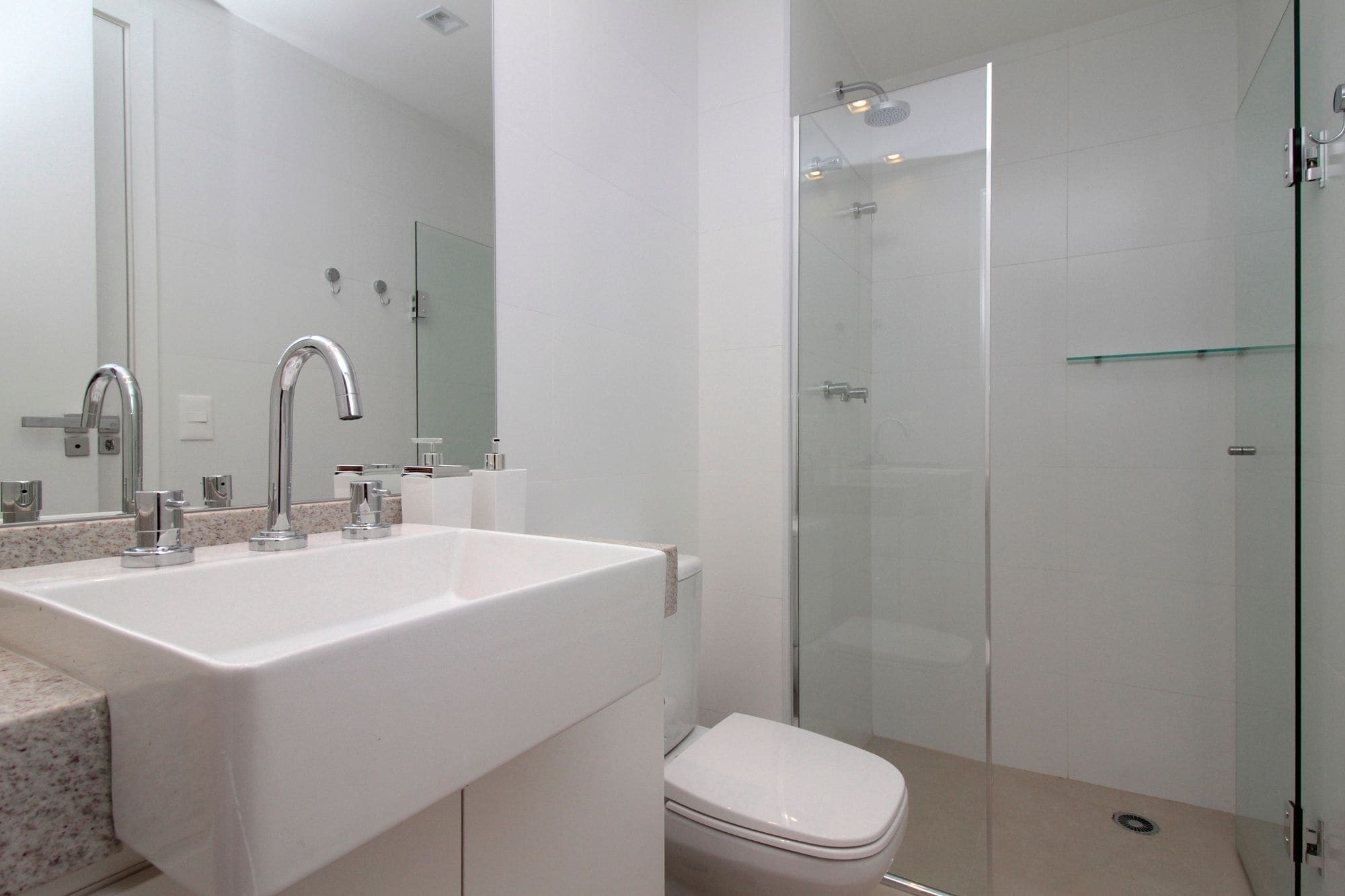 Un baño moderno con un lavabo blanco grande, cabina de ducha de vidrio y un inodoro.