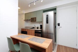 A compact kitchen with a refrigerator, microwave, and dishwasher. - Boulevard Agami (São Paulo)