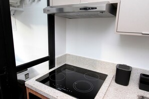 A kitchen with a black induction cooktop, a stainless steel range hood, and a granite countertop. - Boulevard Agami (São Paulo)