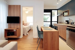 A modern hotel room with a TV, wooden furniture, a dining area, and a kitchen. - Boulevard Agami (São Paulo)