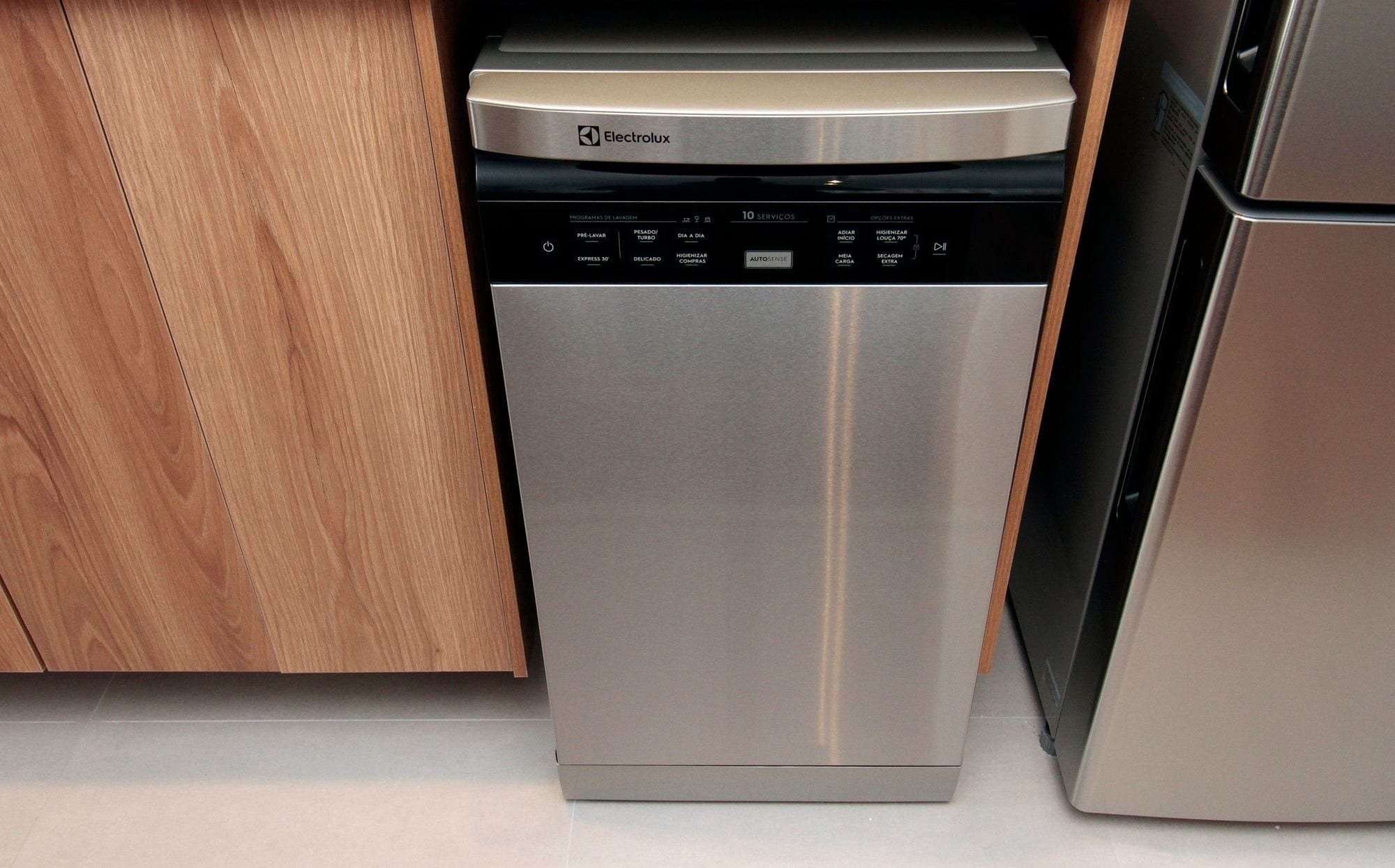 A stainless steel dishwasher with a control panel, located in a kitchen with wooden cabinets.