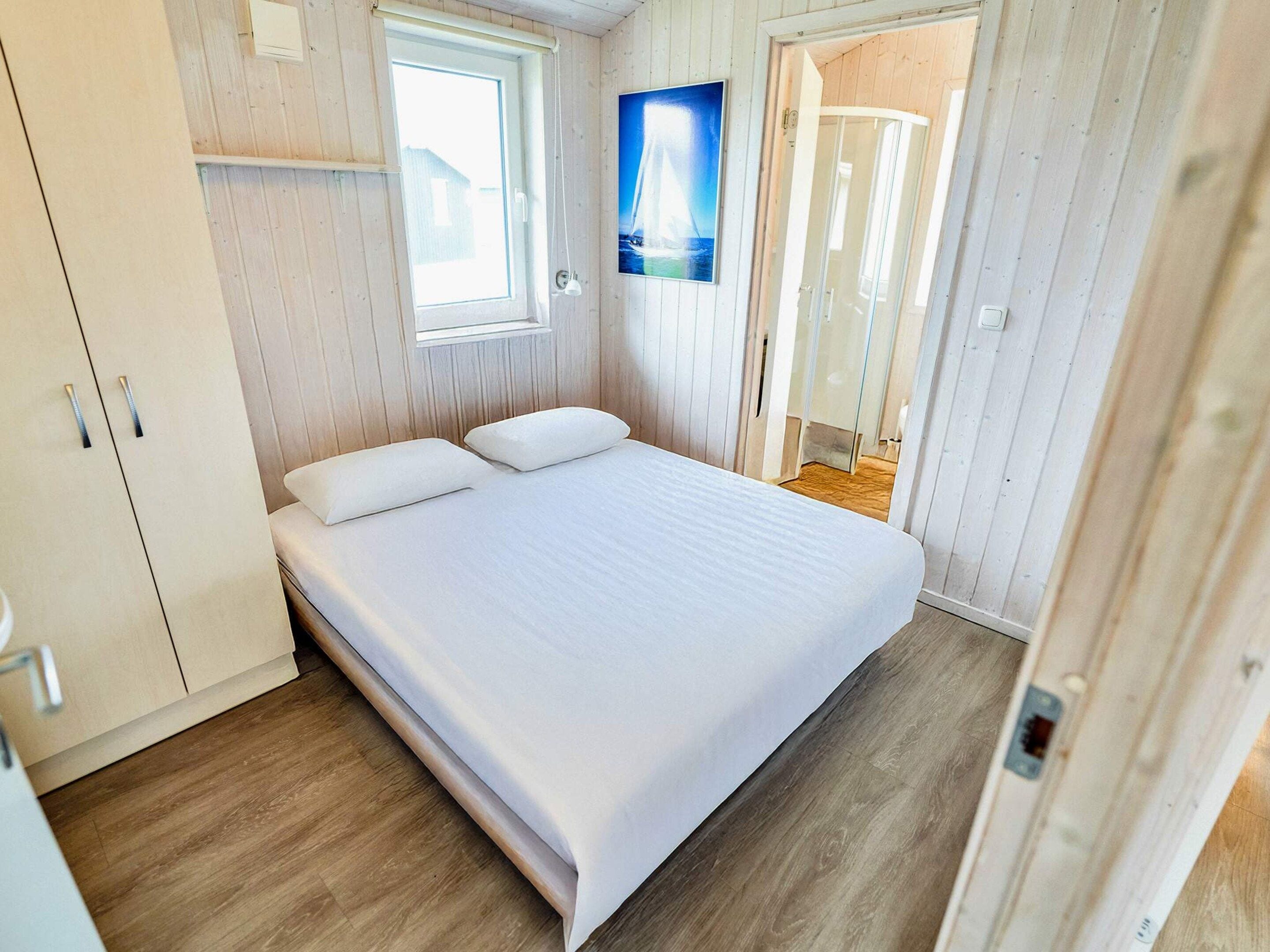 Una habitación con cama, armario, ventana y puerta que da a otra estancia.