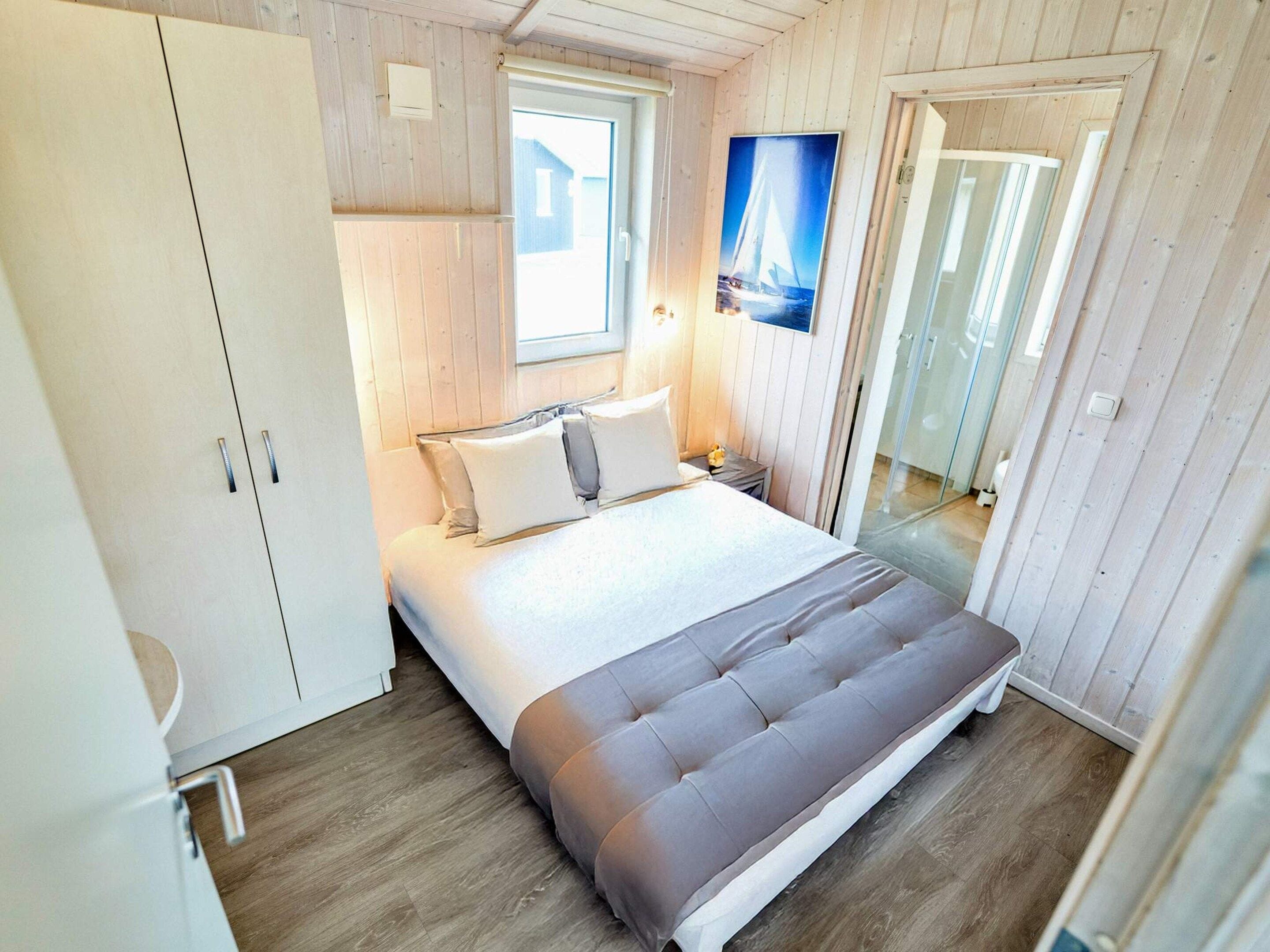 A bedroom with a bed, a window, a door, and a mirror.