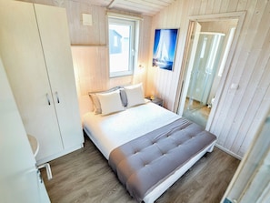 A bedroom with a bed, a window, a door, and a mirror. - 4 Star Holiday Home in Friedrichkoog (Friedrichskoog)