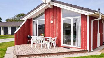 A red building with a covered patio, white furniture, and a satellite dish.