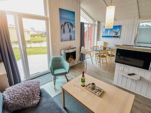 A modern living room with a fireplace, a dining area, and a TV. - 4 Star Holiday Home in Friedrichskoog (Friedrichskoog)