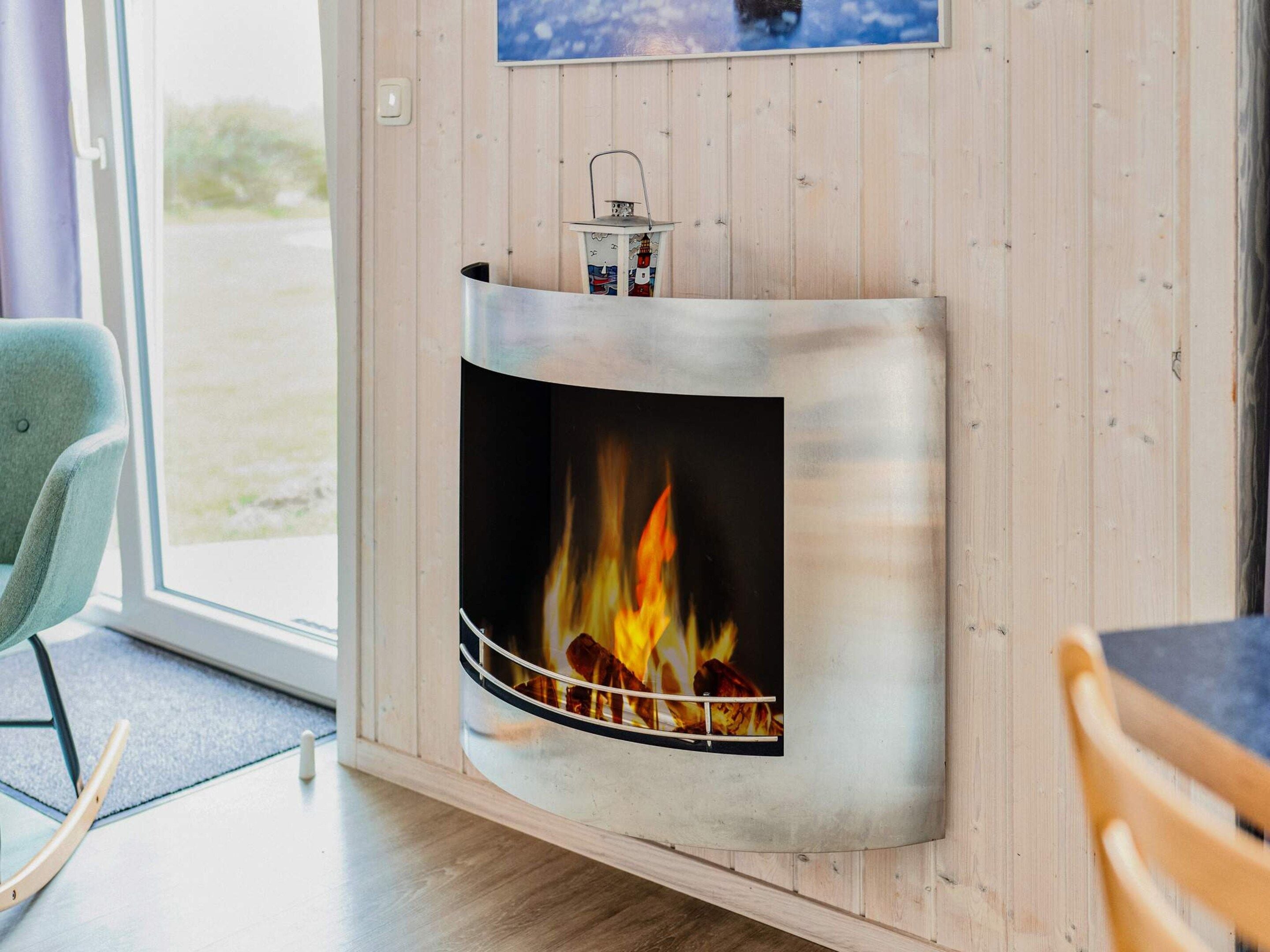 A modern interior with a built-in fireplace, a wooden wall, a window, and a chair.