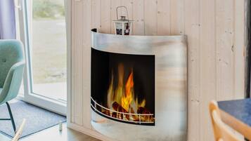 A modern interior with a built-in fireplace, a wooden wall, a window, and a chair.