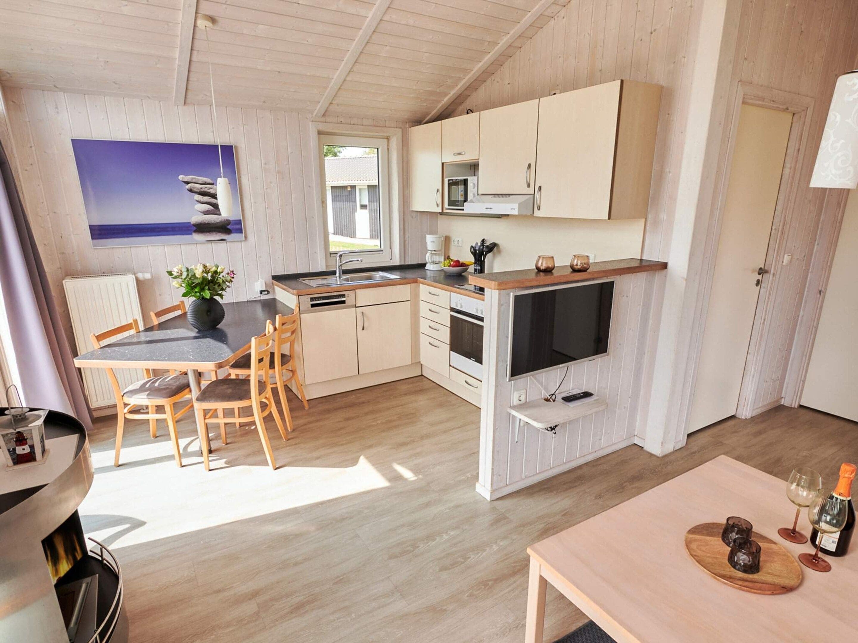 A compact kitchen with wooden cabinets, a dining area with a table and chairs, and a view of the outdoors.