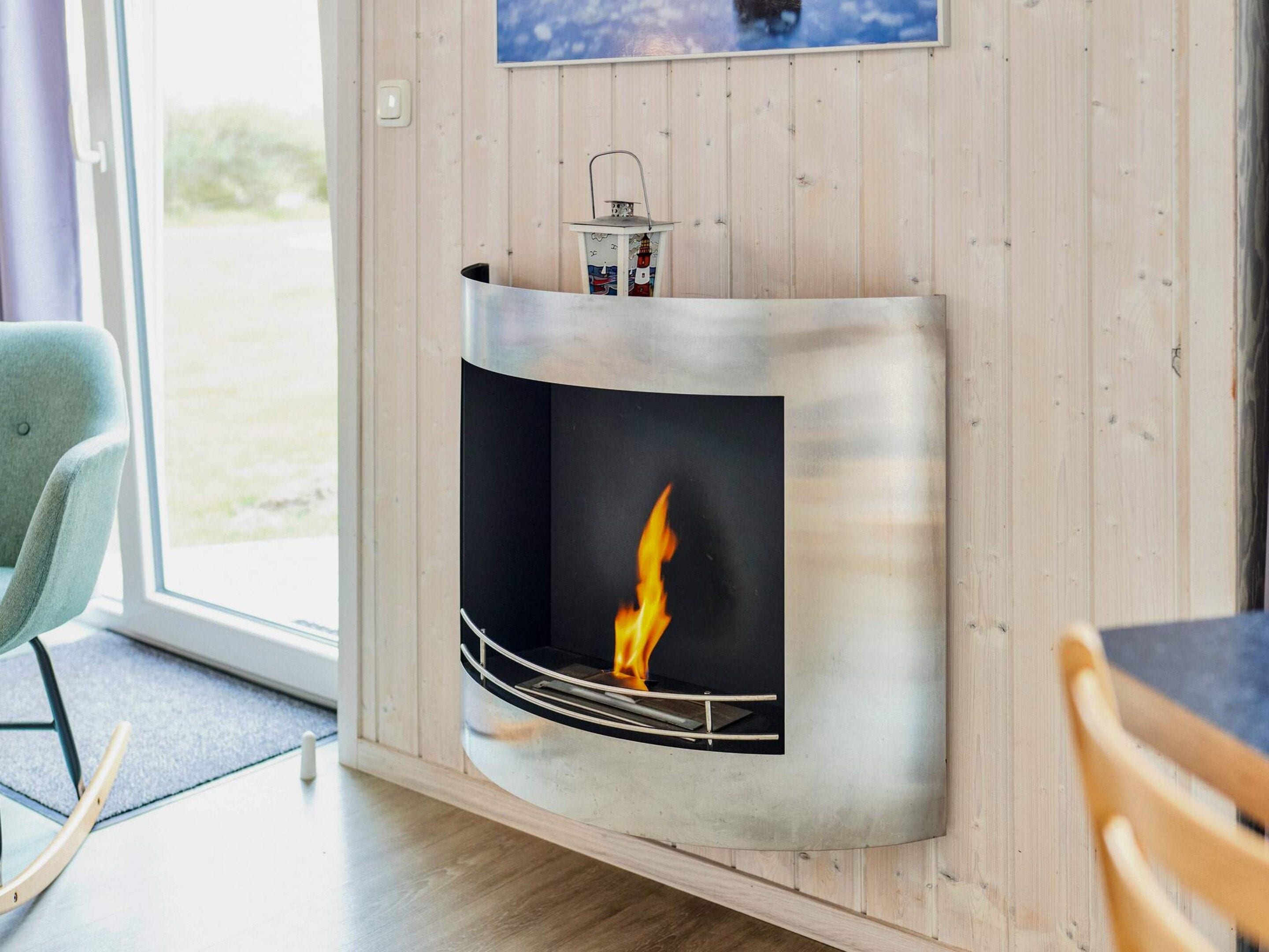 Un interior moderno con chimenea empotrada, pared de madera y vistas a través de un ventanal.
