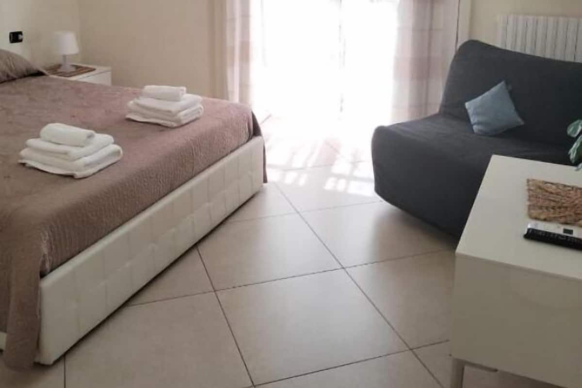 Une chambre d’hôtel avec un lit, un canapé, une petite table et un téléviseur fixé au mur.