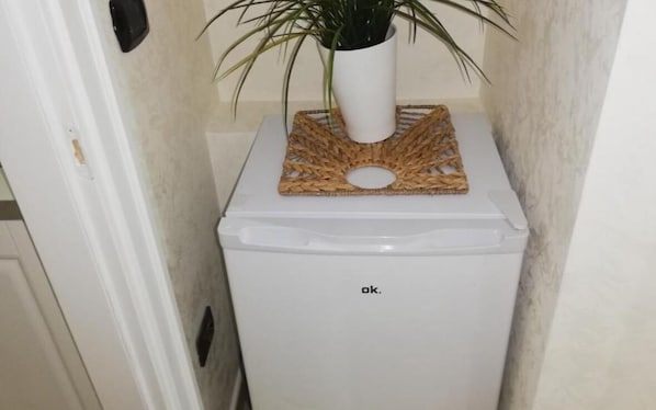 A small white appliance, possibly a refrigerator or a freezer, with a woven mat and a potted plant on top. - Ladolcedimora (Naples)