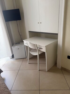 Un dormitorio pequeño y ordenado con una cama individual, una mesita de noche, una silla y un armario.