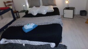Une chambre avec deux lits, une table de chevet, une chaise et un petit meuble.