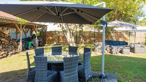 A covered outdoor dining area with wicker furniture and a central table. - Vacation Home with Garden in Hossegor, Near Lake, Town Center & Beaches – Perfect for 4-6 Guests (HOSSEGOR)