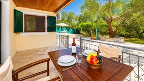 A wooden table set for two with plates, a wine bottle, and a fruit basket. - Villa Old Vineyard - One Bedroom Villa, Sleeps 2 (Paxi)