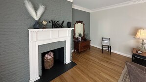 Una habitación con chimenea, un espejo, un aparador, una silla y una lámpara.