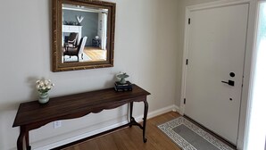 Un pasillo con una consola de madera, un espejo y una puerta.