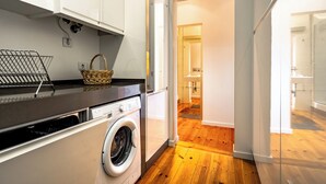 A compact laundry area with a washing machine, a drying rack, and a basket.