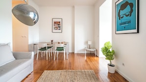 A modern living room with a sofa, dining table, chairs, a lamp, and a potted plant.