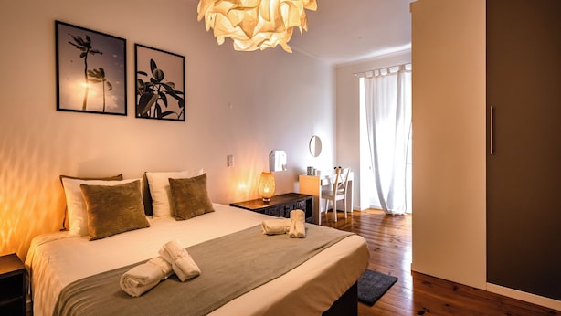 A modern bedroom with a large bed, bedside tables, a desk, and a chair.