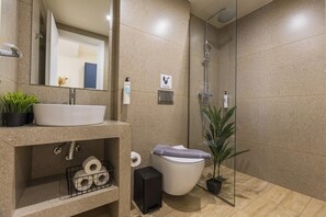 Un bany modern amb un lavabo, vàter i dutxa.
