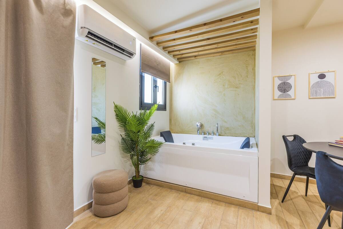Une salle de bain moderne avec une baignoire, une plante en pot et un miroir.