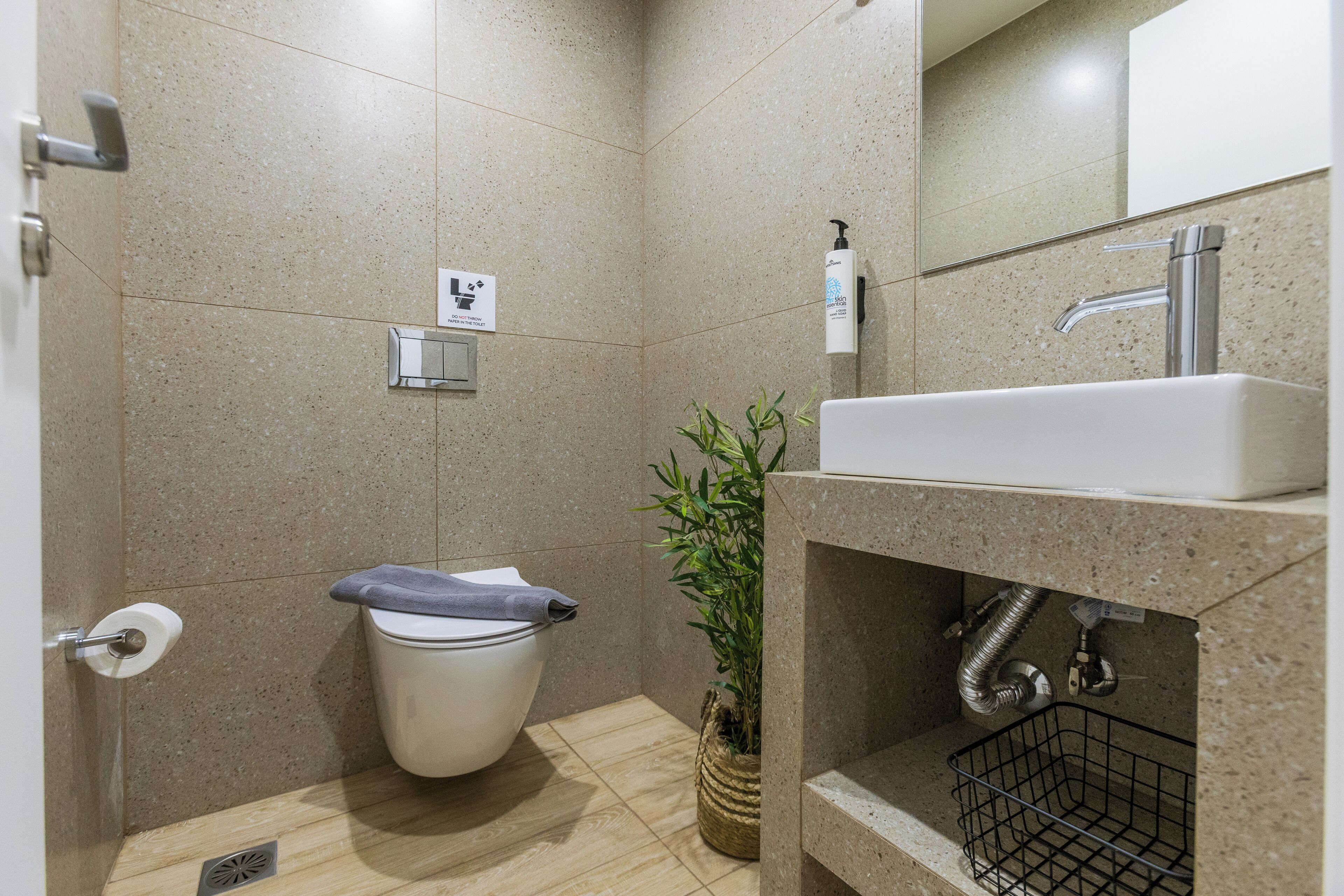 A modern bathroom with a toilet, sink, and a potted plant.