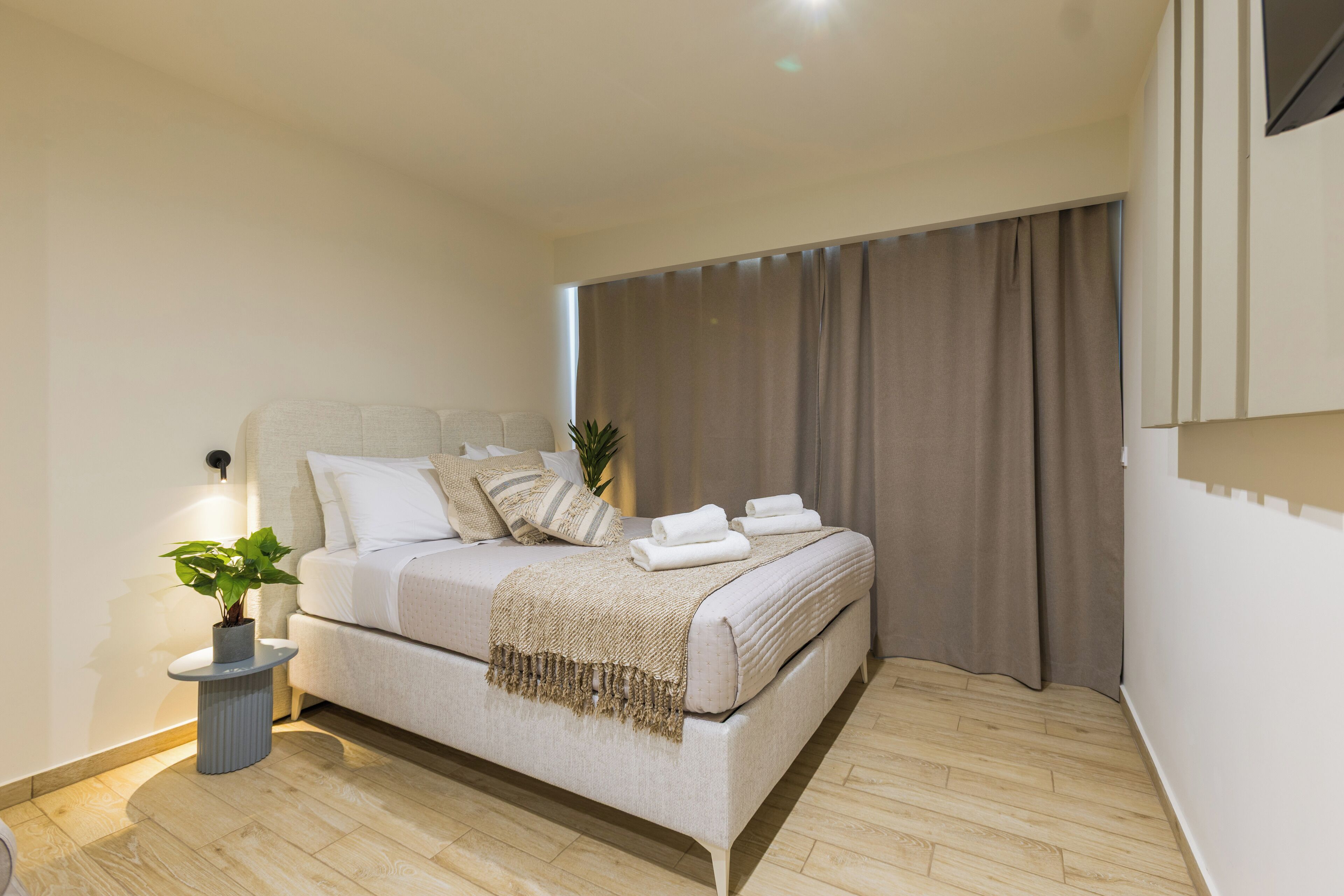 A modern bedroom with a bed, bedside table, and a potted plant.