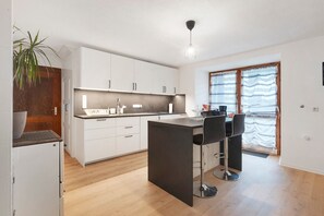 Een moderne keuken met witte kasten, een centraal eiland en een barretje.