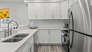 A modern kitchen with white cabinets, stainless steel appliances, and a double sink.